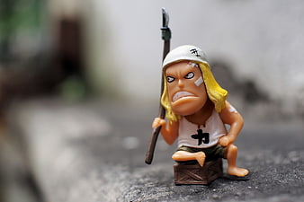 Anime Warrior Figurine Holding Spear On Stone Surface
