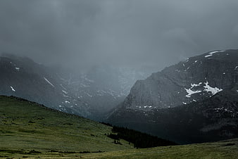Misty Mountain Valley with Green Grass and Snow Patches
