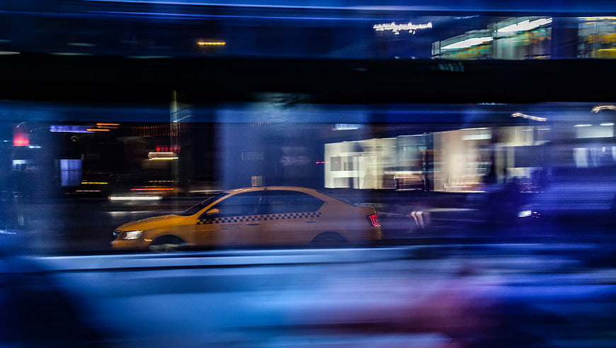 Yellow taxi speeding through city at night with motion blur