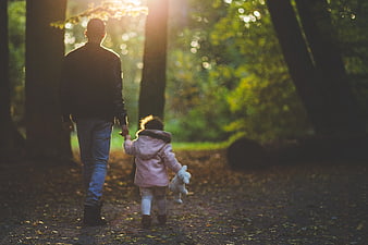 Father and Daughter Walking Hand in Hand in Forest
