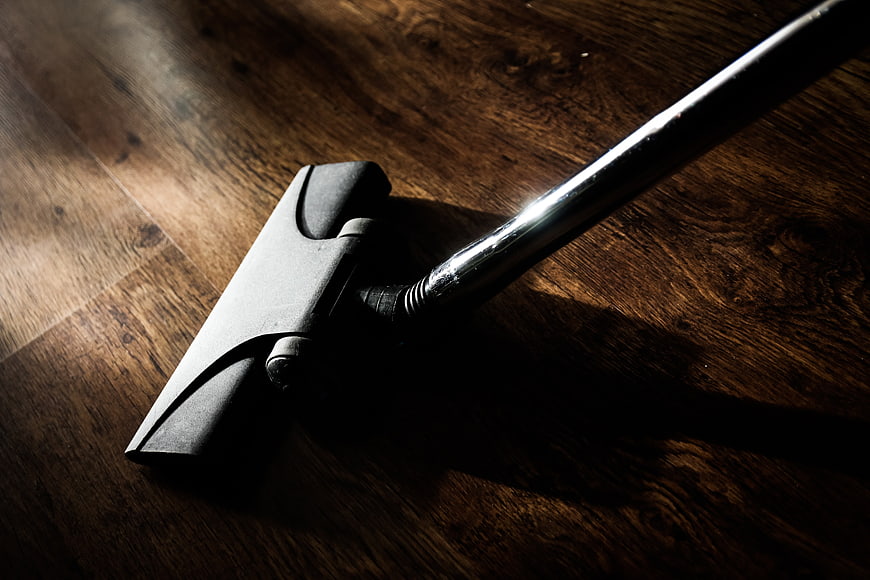 Dramatic Close-Up of Vacuum Cleaner Nozzle on Dark Wood Floor