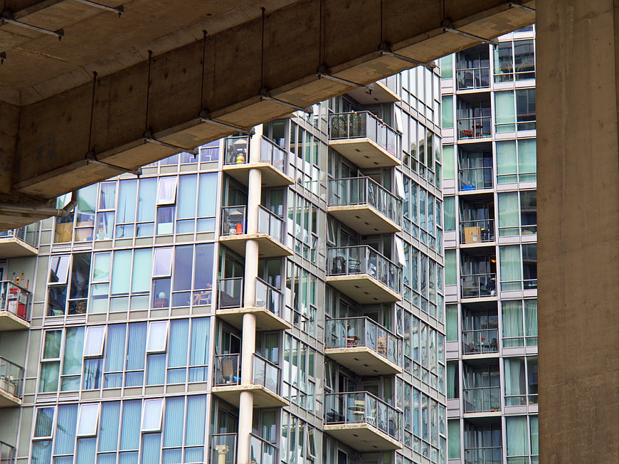 Modern Apartment Building Facade with Balconies Under Concrete Overpass
