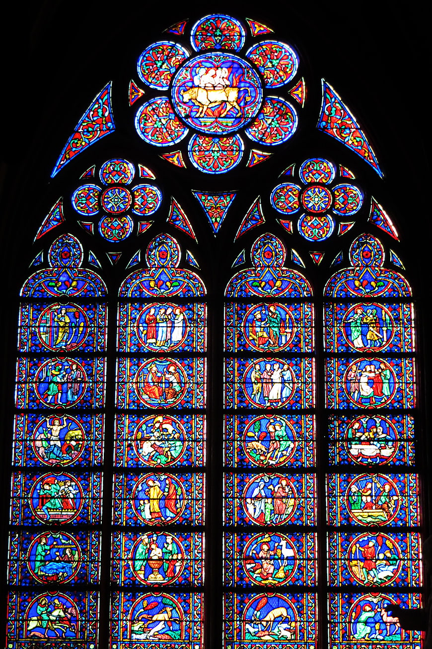 Gothic stained glass window with vibrant religious scenes
