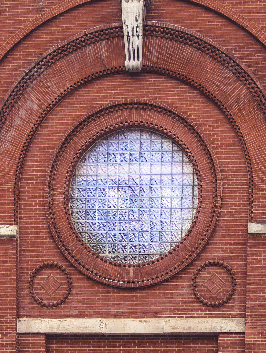Red brick facade with circular glass block window and arch