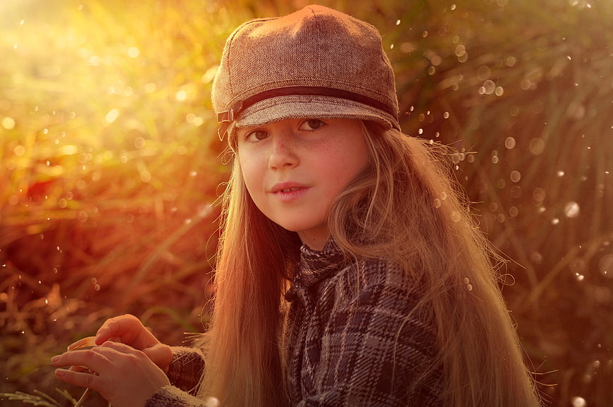 Portrait of a young girl in a cap during golden hour