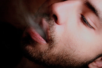 Close-up of man exhaling smoke with closed eyes