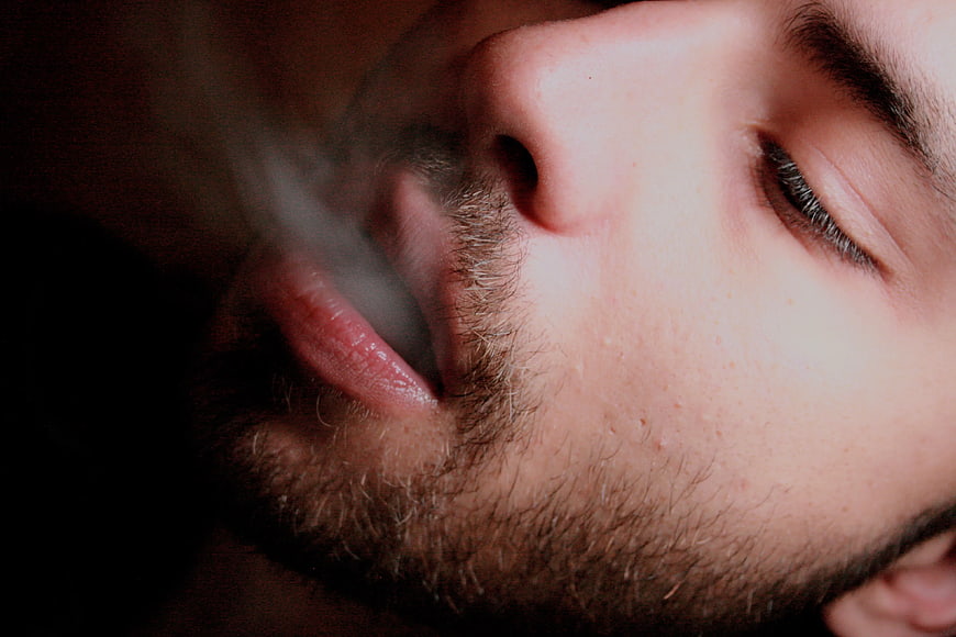 Close-up of man exhaling smoke with closed eyes