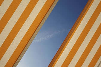 Abstract Orange and White Striped Architecture Against Blue Sky