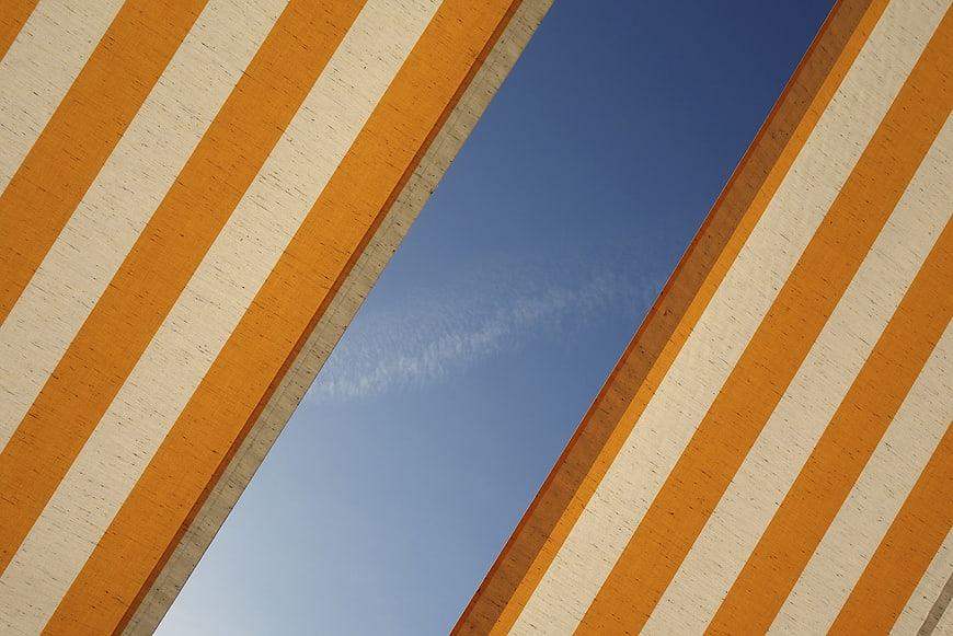 Abstract Orange and White Striped Architecture Against Blue Sky