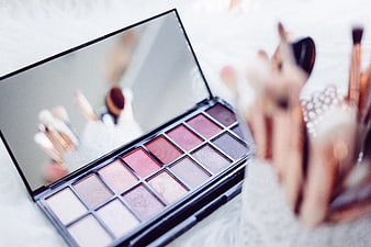 Pink eyeshadow palette with makeup brushes on white background