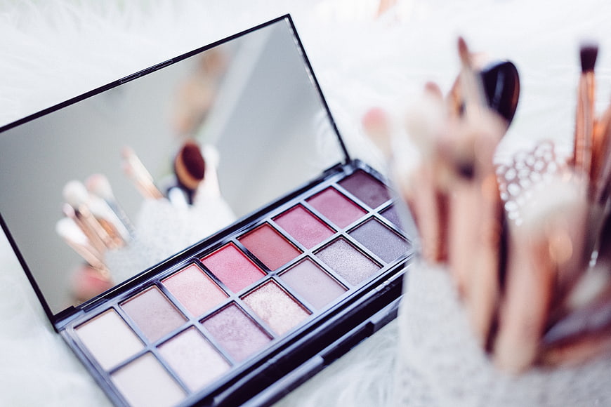 Pink eyeshadow palette with makeup brushes on white background