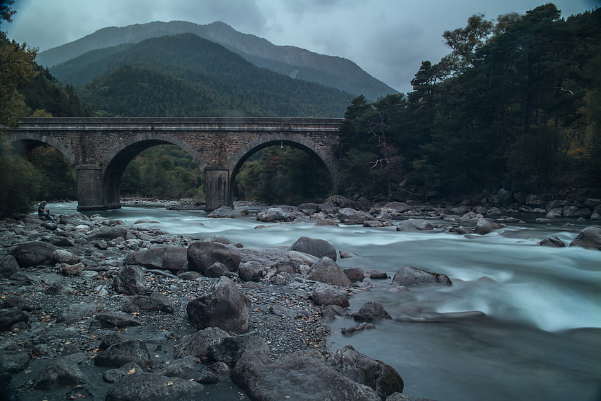 Stone arch bridge over misty river in mountain landscape