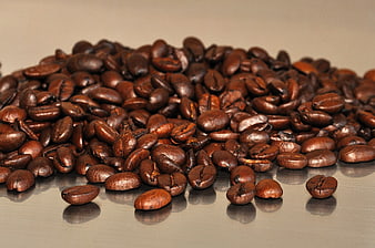 Pile of roasted coffee beans on a reflective surface