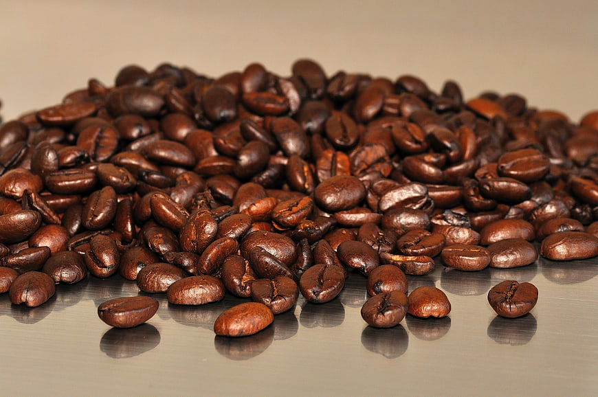 Pile of roasted coffee beans on a reflective surface