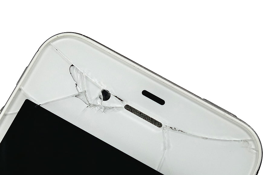 Close-up of cracked white smartphone screen on white background