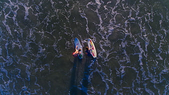 Aerial view of two surfers paddling in ocean waves