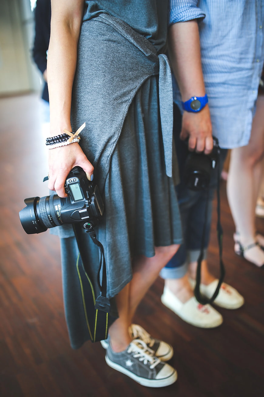 Woman holding DSLR camera with casual sneakers