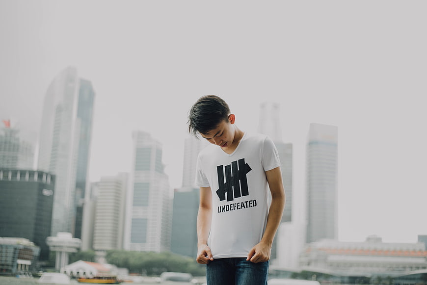 Young man in white t-shirt looking down with city skyline background