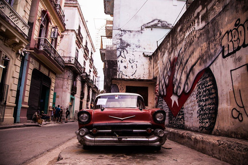 Vintage Red Classic Car Parked on Narrow Street with Graffiti