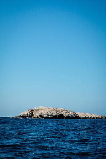 Rocky Island in Blue Ocean Under Clear Sky