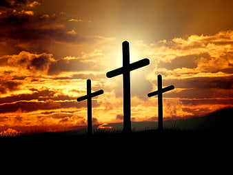 Three Silhouetted Crosses Against Dramatic Orange Sunset Sky
