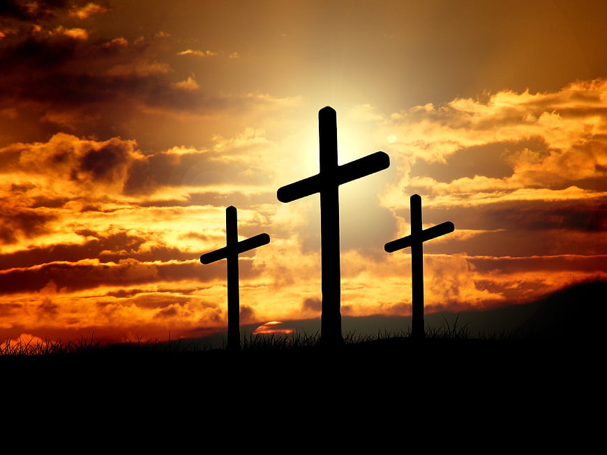 Three Silhouetted Crosses Against Dramatic Orange Sunset Sky