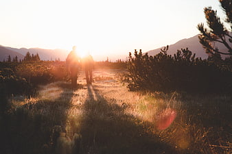 Couple hiking in mountains at golden hour sunset