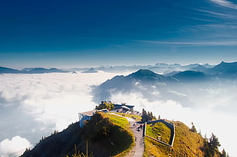 Mountain Peak Above Sea of Clouds with Modern Building
