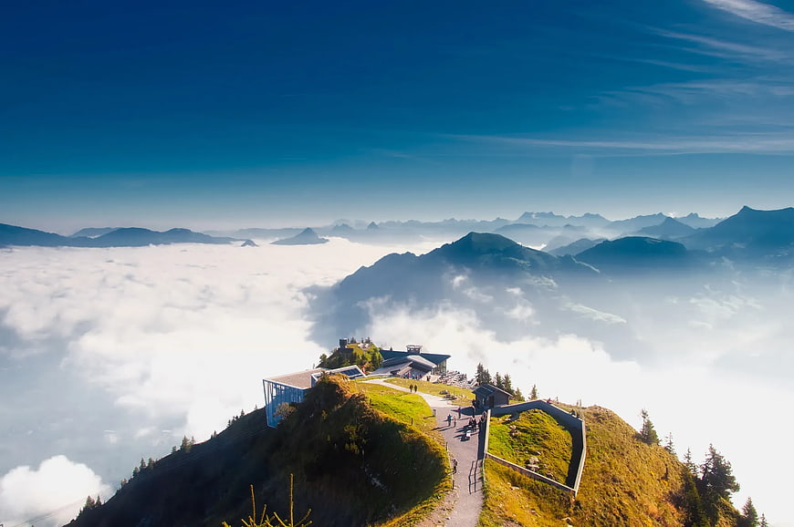 Mountain Peak Above Sea of Clouds with Modern Building