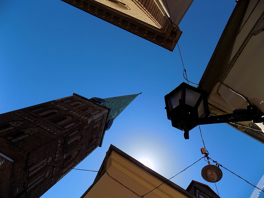 Low angle view of historic church tower and street lamp against blue sky