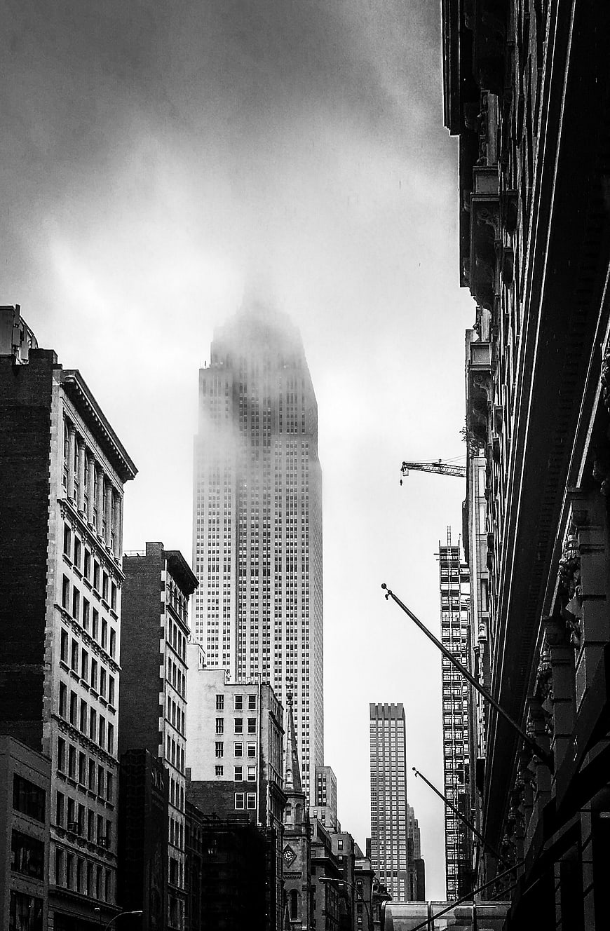 Black and white skyscraper emerging from fog in city