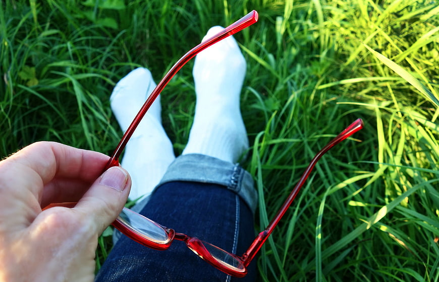 Relaxed POV of Red Glasses Held Over Grass and White Socks