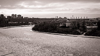 Frozen River Landscape with City Skyline and Industrial Bridge