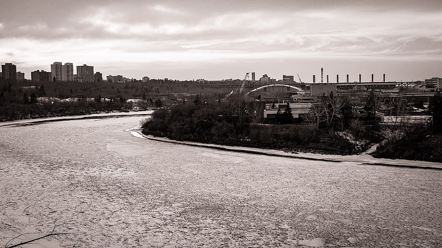 Frozen River Landscape with City Skyline and Industrial Bridge