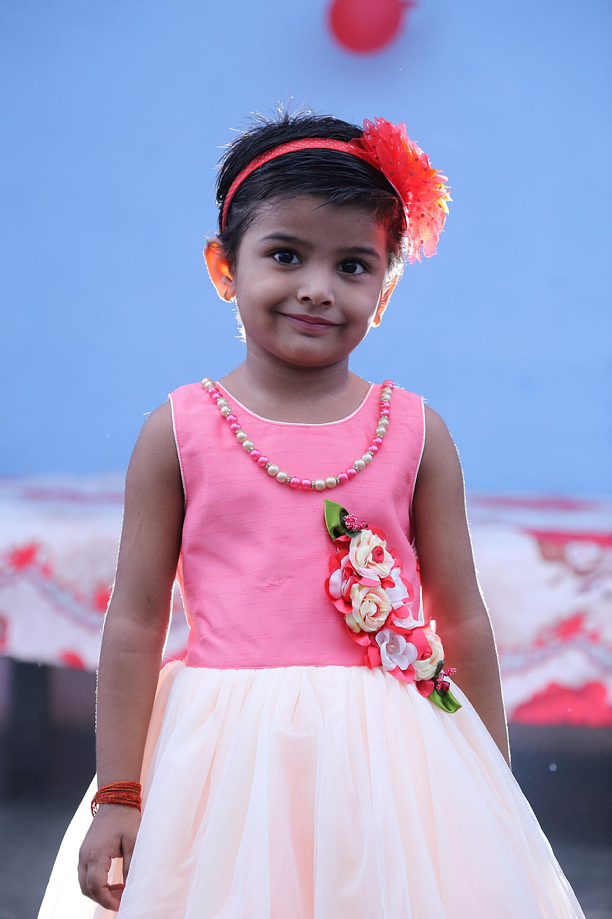 Cute little girl in pink dress smiling outdoors