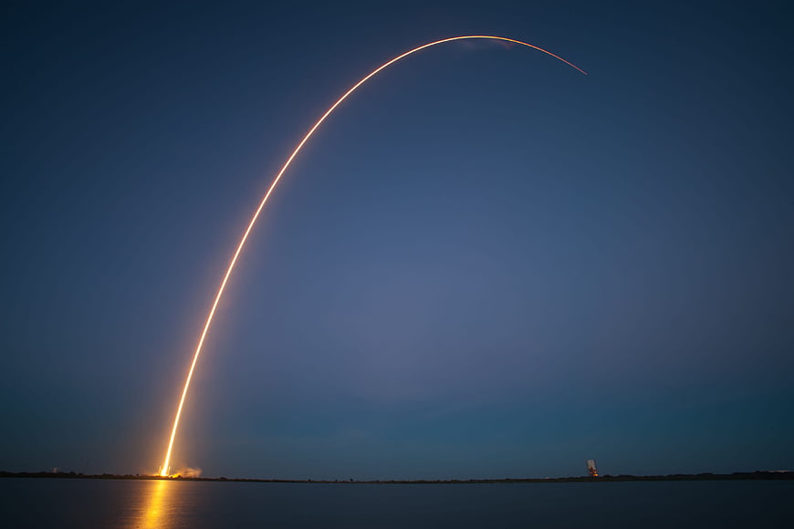 Rocket Launch Trajectory Arc Over Ocean at Night
