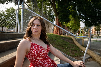Young Woman in Red Floral Dress Sitting on Concrete Steps