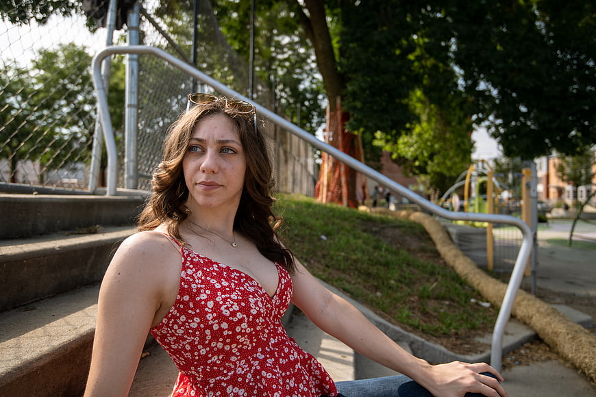 Young Woman in Red Floral Dress Sitting on Concrete Steps