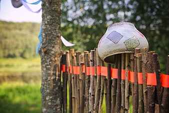 Decorative ceramic pot on rustic wooden fence in countryside