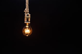 Vintage Edison Light Bulb Hanging On Rope Against Black Background