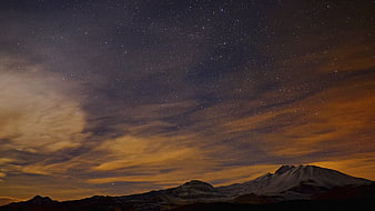 Starry Night Sky Over Snow-Capped Mountain Peak