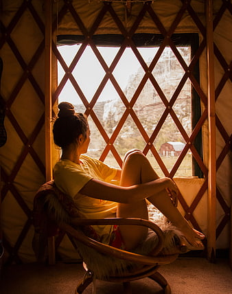 Woman sitting in chair looking out yurt window