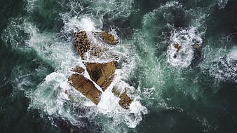 Aerial View of Turbulent Ocean Waves Crashing on Rocks