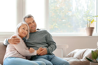 Happy Senior Couple Sitting Together on Sofa at Home