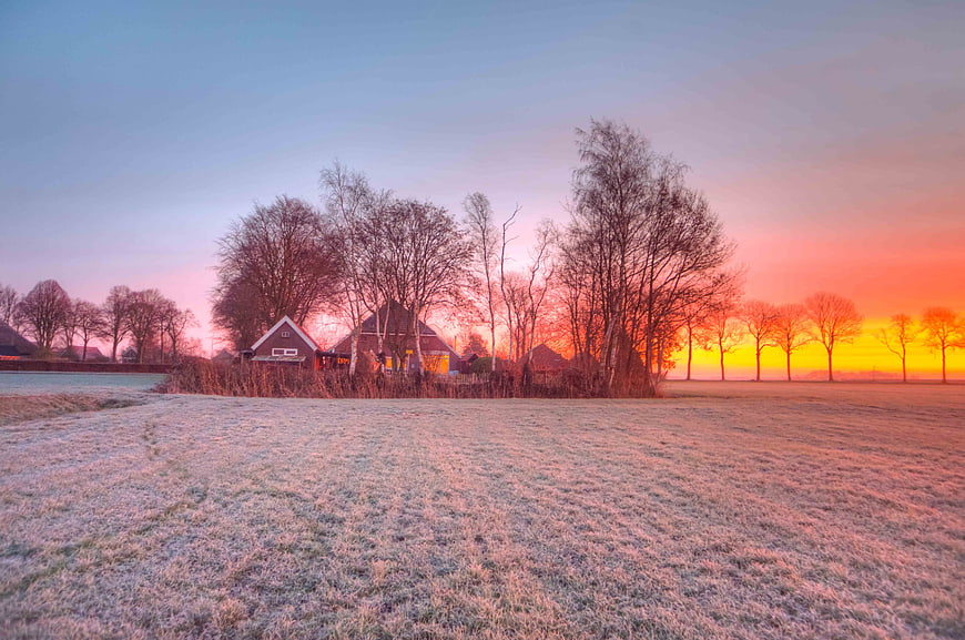 Frosty rural landscape with houses at sunrise