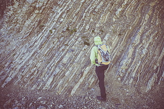 Hiker with Backpack Standing Before Striated Rock Formation