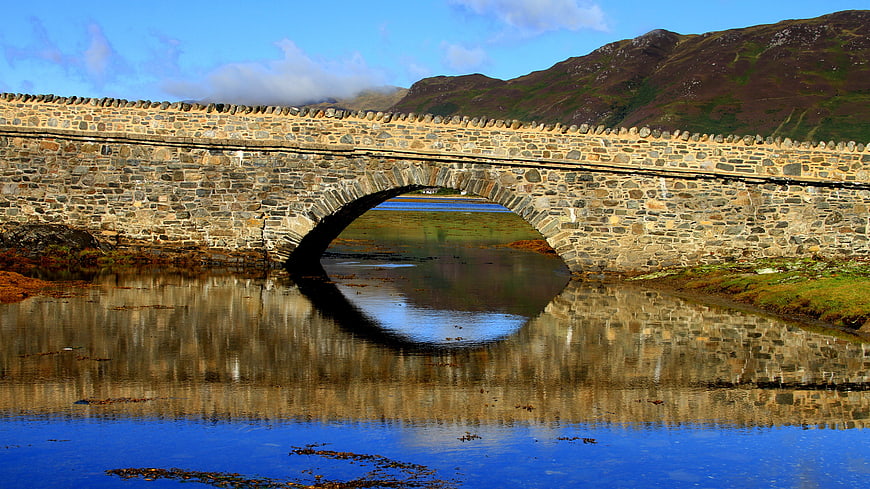 Stone arch bridge reflection in calm water Scotland