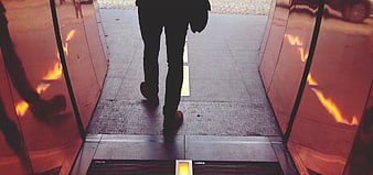 Man Walking Through Glass Doors with Orange Reflections