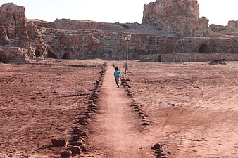 Child running on path toward ancient ruins