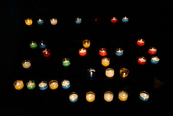 Colorful lit candles arranged in rows on dark background